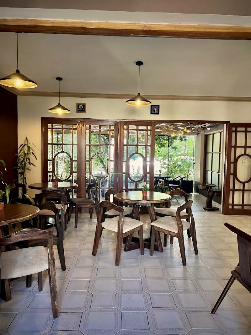 Sala con mesas de madera y puertas de vidrio con marcos ovalados hacia el jardín.